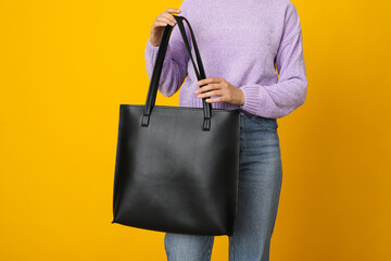 Black bag in hand on yellow background