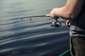 Freshwater fishing in summer. A fisherman using a spinning with a spinning reel to catch predatory...