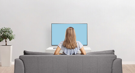 Rear view shot of a woman sitting on a sofa and watching tv