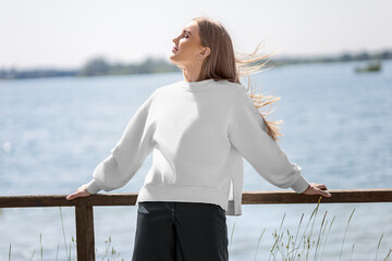 Mockup of a white sweatshirt on a blonde girl on the background of the river, quay, fashionable...