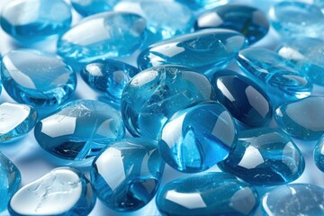 Close-up of varied blue glass stones and pebbles against a reflective backdrop