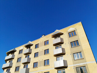 Fototapeta premium Facade of new multi-story residential building. Sale and rental apartments. Housing development. Cityscape. City life. Real estate. Blue sky. Mortgage concept. Condos. Interest Rate Increase. Flat.
