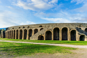 landscape of old ancient building of Roman arena with greeen grass foreground and  beautiful blue cloudy sky background