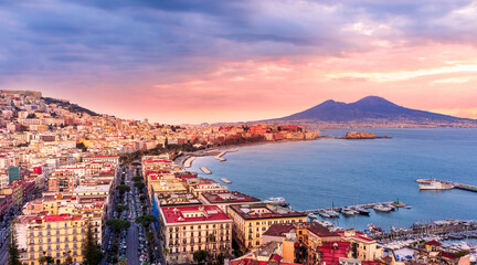 amazing Naples landscape of Vomero hill with beautiful streets and buildings of Napoli city, blue sea gulf and volcano Vesuveus with sunset of sunrise cloudy sky on background © Yaroslav