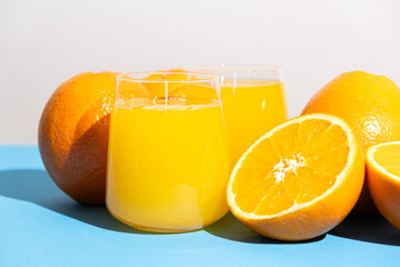 Orange juice in a glass and half a fresh orange on a blue background
