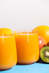 Multi-fruit juices in glasses among fresh fruits.