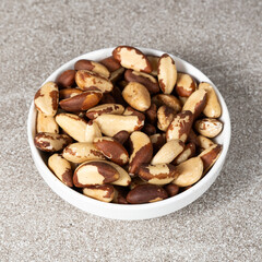 Brazil nuts in plate on grey background