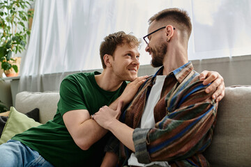 Fototapeta premium Gay couple creating trendy attire, sitting together on top of a couch in a designer workshop.