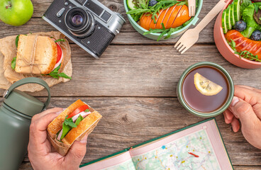 a man snacking on a sandwich and tea while planning a hiking route. travel concept