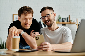 Two men, designers, passionately collaborate on a laptop for their trendy attire.