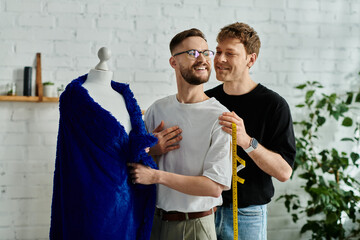 Two male designers standing beside a dress on a mannequin in a creative workshop.