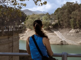 A young woman tourist looking at the water reservoir from the dam Conde De Guadalhorce in...