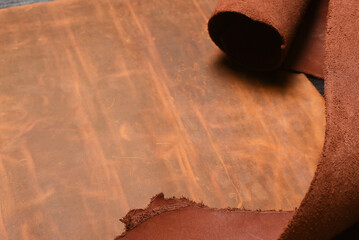 Brown leather rolled up pieces scrolls on the black table background. Top view.
