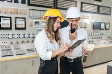 Asian male and female engineers Use skills to control machinery in a nuclear power plant. There is...