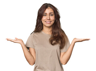 Middle Eastern woman in studio makes scale with arms, feels happy and confident.