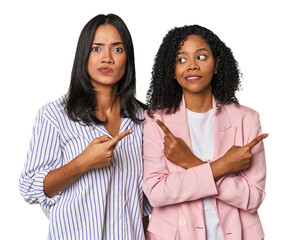 Young Latin businesswomen in studio points sideways, is trying to choose between two options.