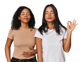 Young Latin friends in studio relaxes after hard working day, she is performing yoga.