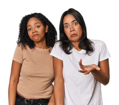 Young Latin friends in studio doubting and shrugging shoulders in questioning gesture.