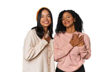 Young Latin friends together in studio has friendly expression, pressing palm to chest. Love concept.