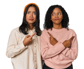 Young Latin friends together in studio points sideways, is trying to choose between two options.