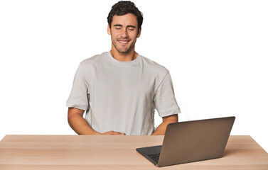 Hispanic young man working on laptop laughs and closes eyes, feels relaxed and happy.