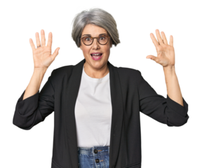 Caucasian mid-age female in business suit receiving a pleasant surprise, excited and raising hands.