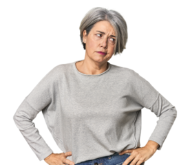 Caucasian mid-age female on studio background confused, feels doubtful and unsure.