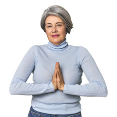 Caucasian mid-age female on studio background praying, showing devotion, religious person looking...