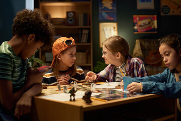 Happy schoolgirl in eyeglasses looking at one of her friends during discussion of characters of...