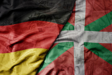 big waving realistic national flag of basque country and national flag of germany on a euro money banknotes background. finance concept.