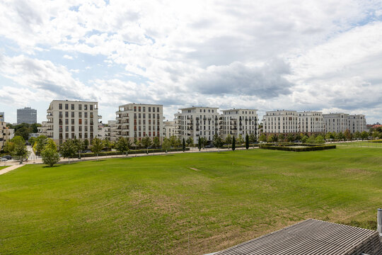 Moderne Wohnanlage mit wei&szlig;en Mehrfamilienh&auml;usern an einer weitl&auml;ufigen Gr&uuml;nfl&auml;che in einem zeitgem&auml;&szlig;en Stadtquartier