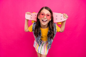 Photo of amazed positive kid girl hold skateboard look isolated bright color background