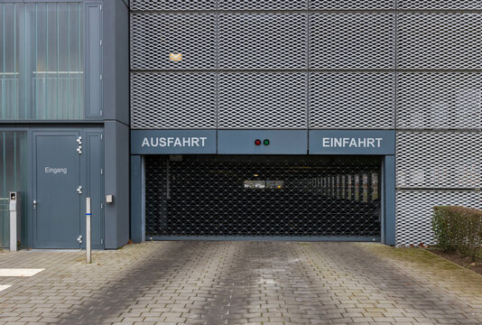 Moderne Parkhausfassade mit markierter Ein- und Ausfahrt sowie einem geschlossenen Gitterrolltor