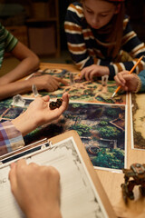 Hand of youthful girl holding group of dice before throwing them on board with picture of magic...