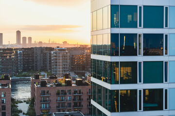 Moderne Glasfassade in Kopenhagen bei Sonnenuntergang mit Blick auf Wasser und Stadtviertel
