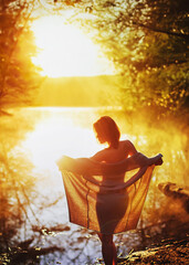 A young woman enjoy sunrise on the water. Poster with copy space.