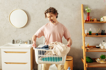 Handsome man in cozy homewear holds laundry basket in bathroom.