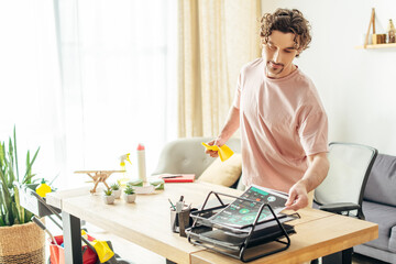 A man in cozy homewear stands in front of a table with a laptop on it.