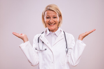 Portrait of mature female doctor gesturing on gray background.