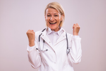 Portrait of  excited mature female doctor gesturing  on gray background.