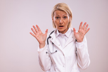 Portrait of mature female doctor in panic on gray background.