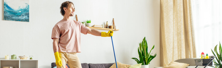 A man in cozy homewear mopping the living room floor.
