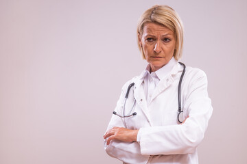 Portrait of angry mature female doctor  on gray background.