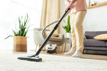 Man in action, using vacuum to clean carpet.