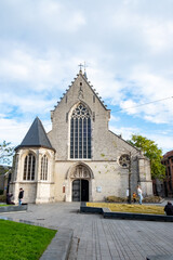 Beside a tower stands a historic Gothic stone church with large windows, showcasing impressive...