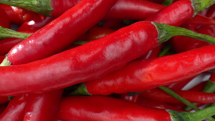 Witness the red chili peppers in exquisite detail, as their ridges and curves become a mesmerizing landscape in this macro, showcasing the beauty of the small and spicy. Food concept. 
