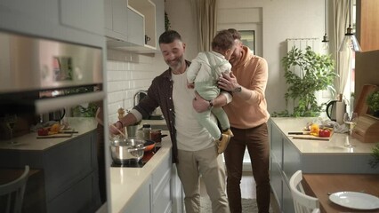 Gay couple cooking in kitchen while playing with their baby