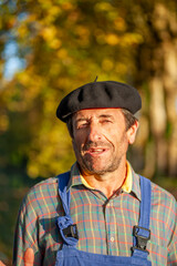 Portrait of a Frenchman, wearing a beret and blue dungarees smiling and gesticulating to camera
