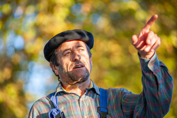 Portrait of a Frenchman, wearing a beret and blue dungarees smiling and gesticulating to camera