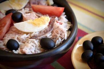 Mediterranean rice salad with tuna, olives, eggs, tomatoes, anchovies close-up
